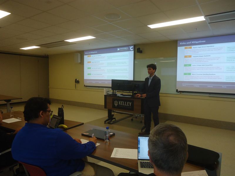 A member presenting a stock pitch at the Kelley podium to a panel of judges