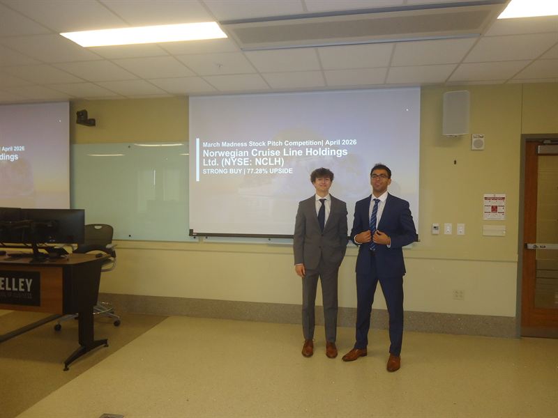 Two members in suits beside a Norwegian Cruise Line pitch slide